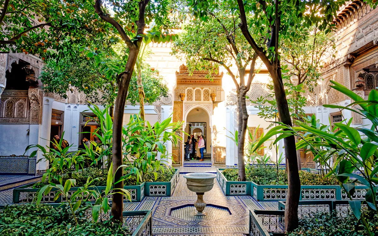 Bahia Palace courtyard with lush greenery and intricate archway in Marrakech, Morocco.
