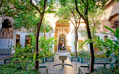 Bahia Palace courtyard with lush greenery and intricate archway in Marrakech, Morocco.