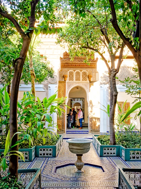 Bahia Palace courtyard with lush greenery and intricate archway in Marrakech, Morocco.