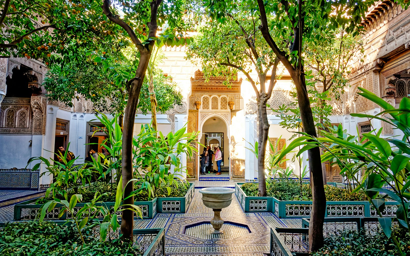 Bahia Palace courtyard with lush greenery and intricate archway in Marrakech, Morocco.