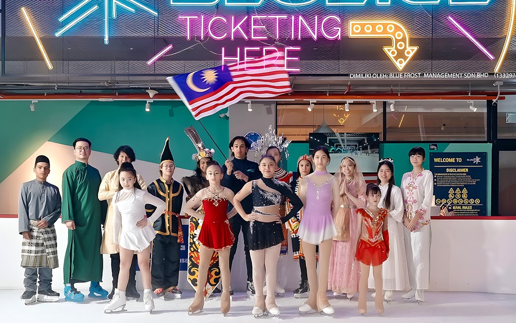 Ice skaters in colorful costumes at Blue Ice Snow Park, 163 Retail Park, with a neon sign above.