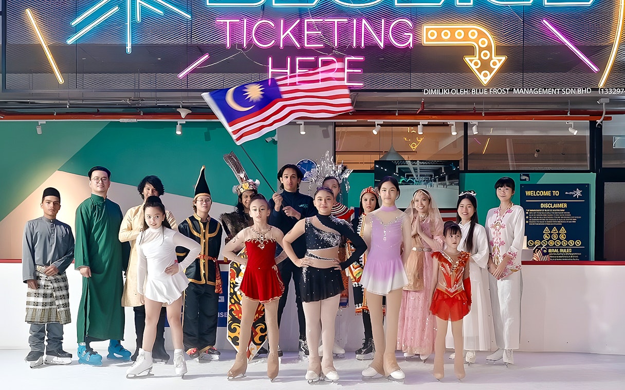 Ice skaters in colorful costumes at Blue Ice Snow Park, 163 Retail Park, with a neon sign above.