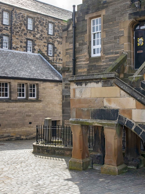 Edinburgh Castle courtyard with historic stone buildings and prison sign.