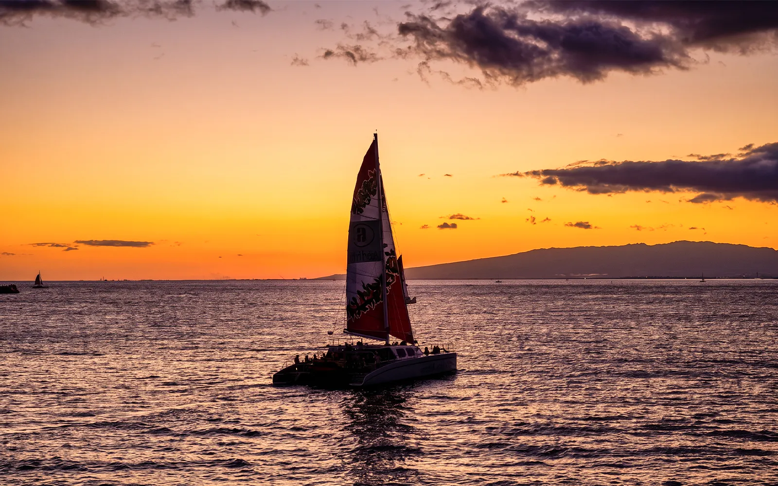 Catamaran sailing at sunset near Oahu during Kaula Kai Sunset Sail.