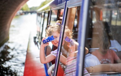 Child looking through binoculars on Amsterdam canal cruise.