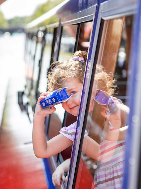 Child looking through binoculars on Amsterdam canal cruise.