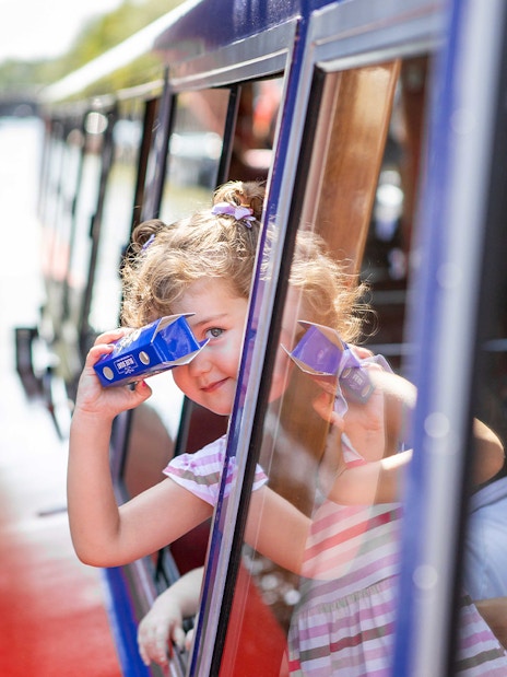 Child looking through binoculars on Amsterdam canal cruise.