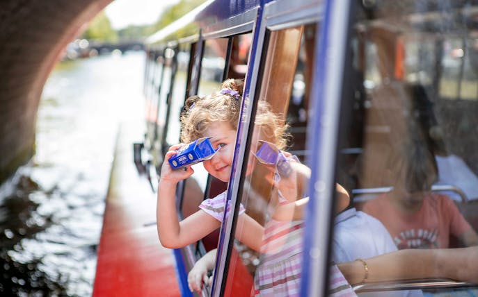 Child looking through binoculars on Amsterdam canal cruise.
