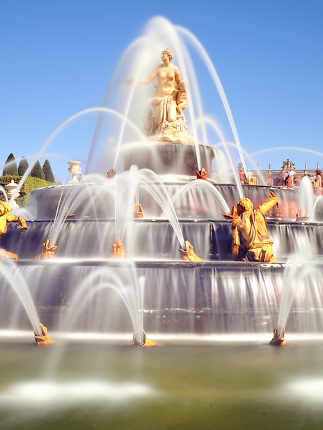 Fountain with golden statues in the Garden of the Palace of Versailles.