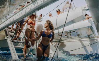People enjoying a mini cruise to Papagayo Beaches from Lanzarote, swimming near a boat.