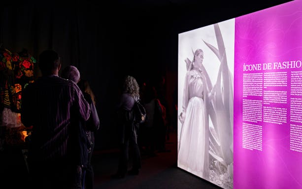 Visitors viewing Frida Kahlo exhibit with biography text and photo display.