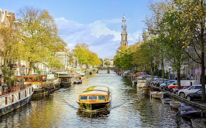 Canal cruise boat on Amsterdam's canal with Westerkerk in the background.