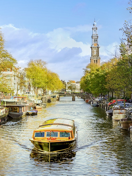 Canal cruise boat on Amsterdam's canal with Westerkerk in the background.