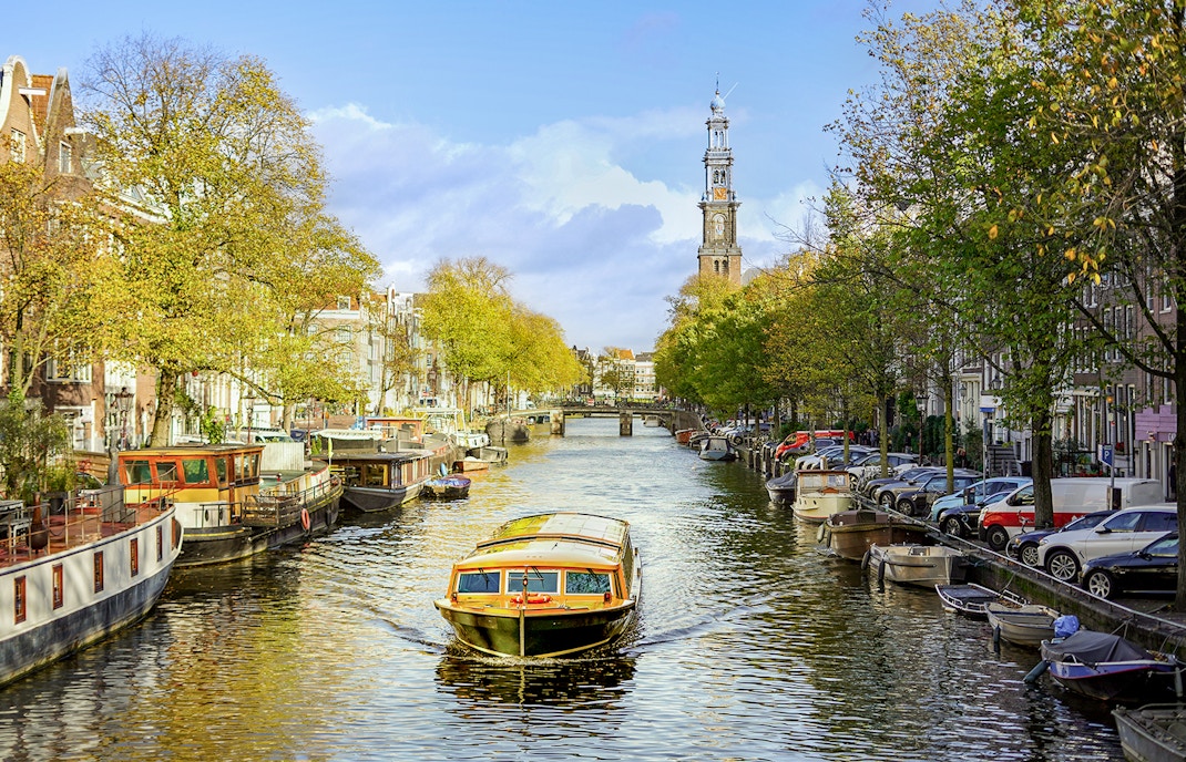 Canal cruise boat on Amsterdam's canal with Westerkerk in the background.