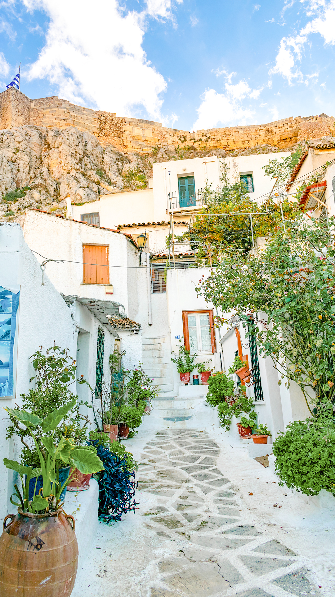 Narrow stone path with whitewashed houses in Anafiotika, Athens, under a clear blue sky.