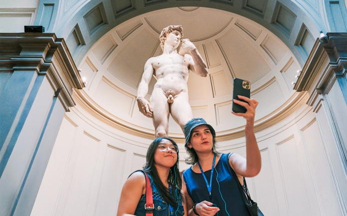 Guests taking a selfie in front of Michelangelo's David in Florence.