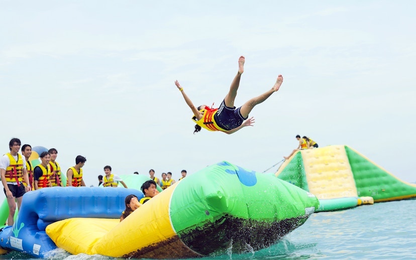 Girl bouncing off inflatable mat at HydroDash water park, Singapore.