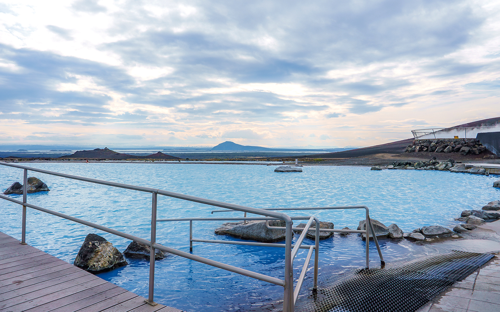Myvatn Nature Baths with geothermal pool and distant volcanic landscape.
