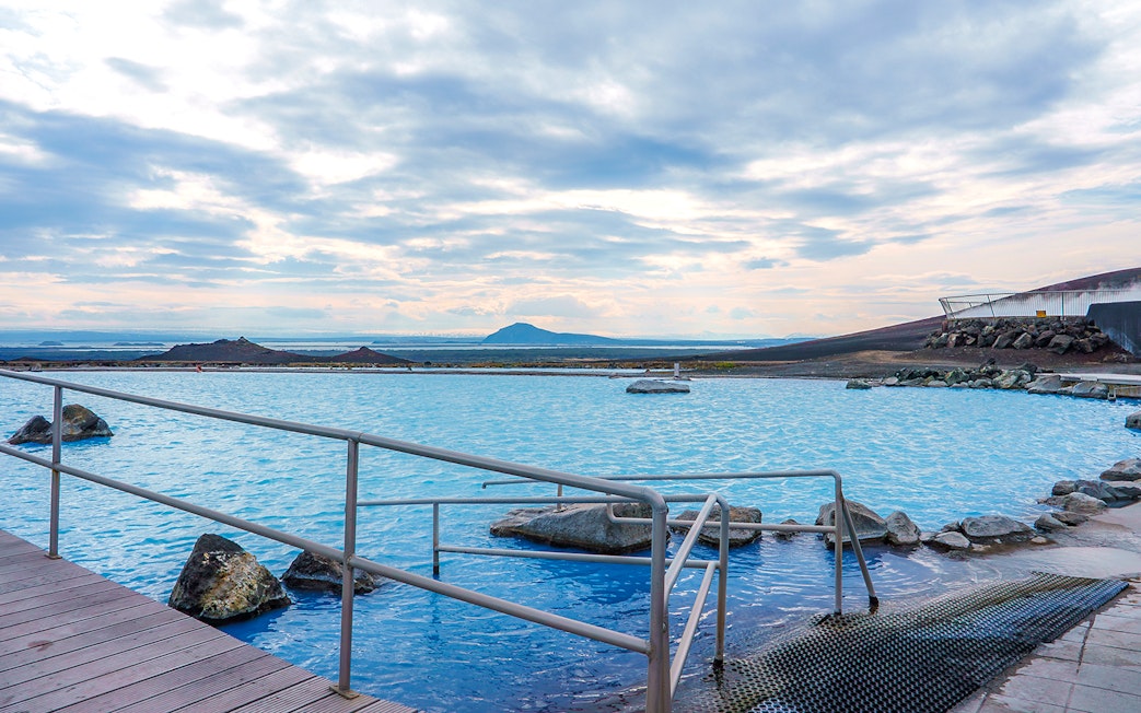 Myvatn Nature Baths with geothermal pool and distant volcanic landscape.