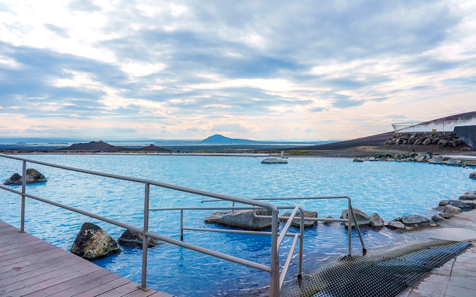 Myvatn Nature Baths with geothermal pool and distant volcanic landscape.
