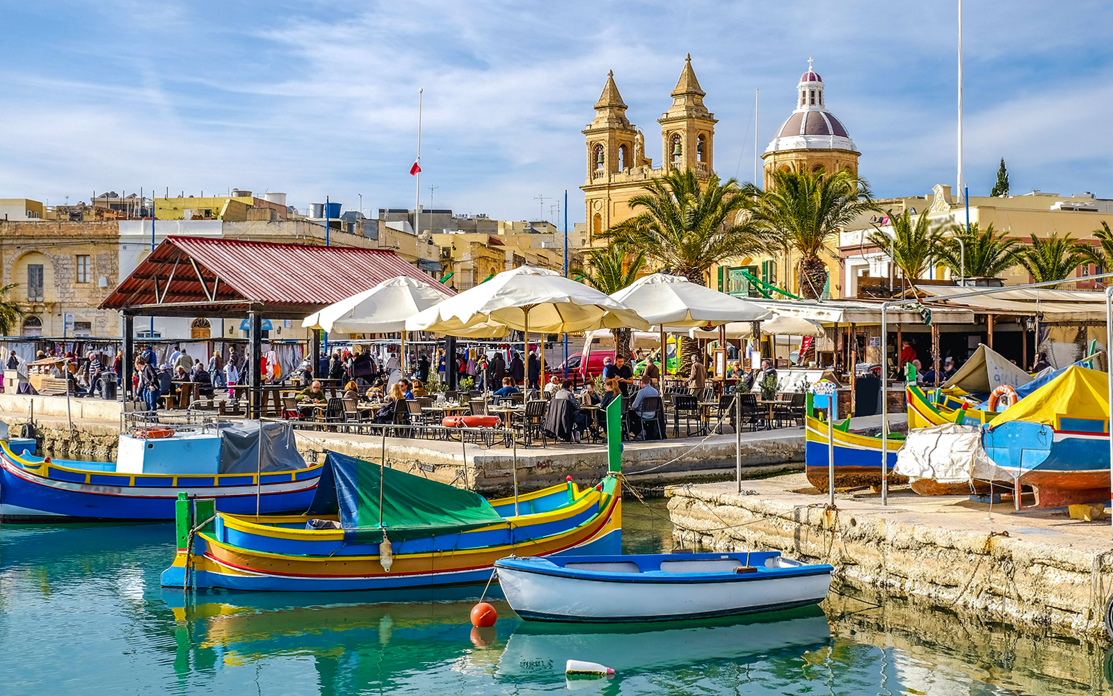 Marsaxlokk fishing boats and Sunday market with church in background, Malta.
