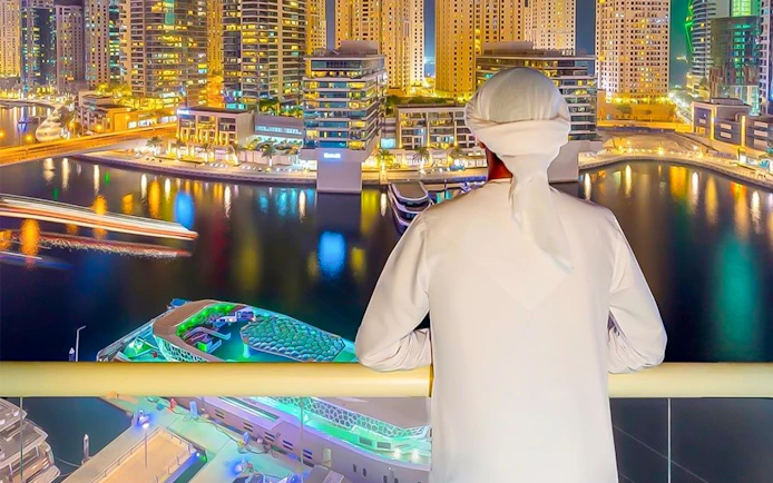 Person overlooking Dubai Marina skyline from a yacht during a dinner cruise.