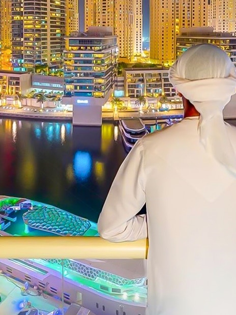 Person overlooking Dubai Marina skyline from a yacht during a dinner cruise.