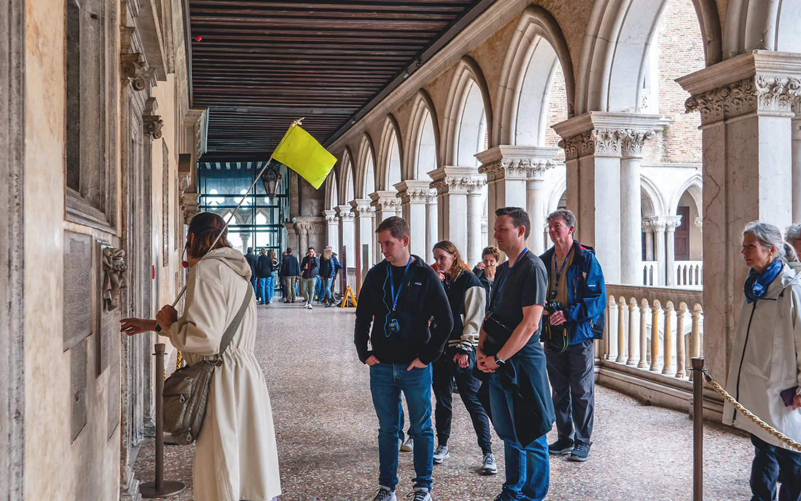 Visitors on a guided tour inside Doge's Palace, Venice, observing historical details.