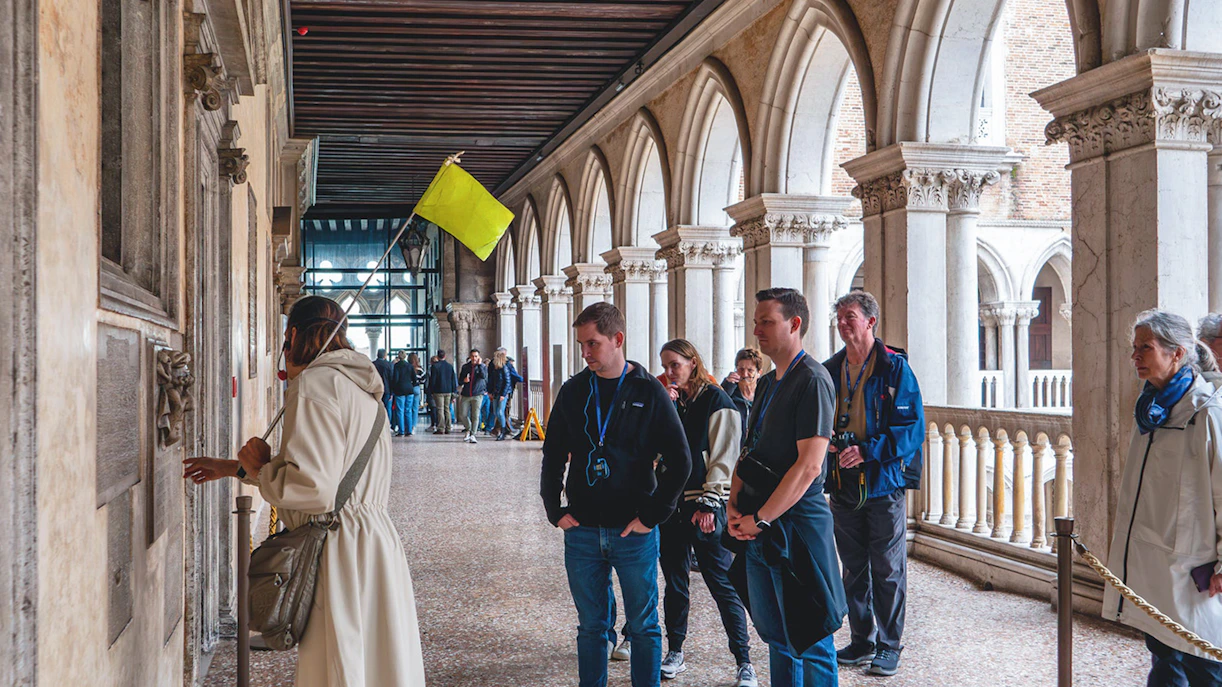 Visitors on a guided tour inside Doge's Palace, Venice, observing historical details.