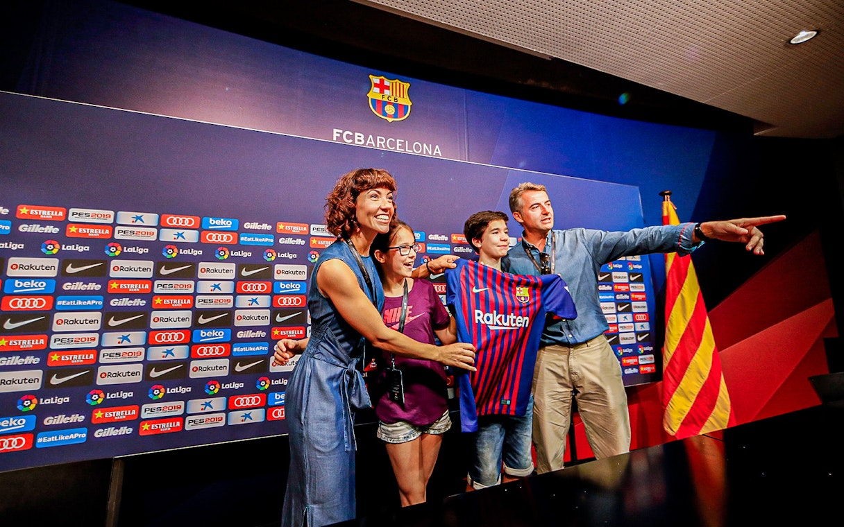 Family posing with FC Barcelona jersey at Camp Nou press room.