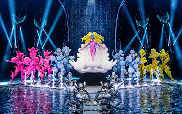 Performers in colorful costumes on stage at the FALLING | IN LOVE Grand Show, Friedrichstadt Palast.