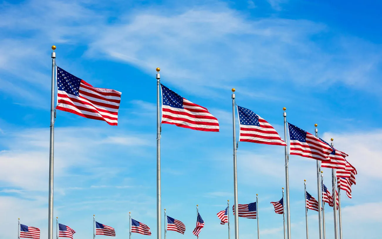 American flags waving at Washington National Mall under a blue sky.