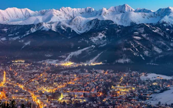 Zakopane town at dusk with snow-covered Tatra Mountains, view from Kraków day trip.
