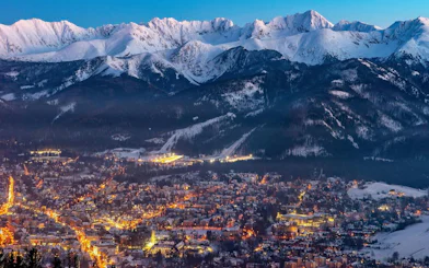 Zakopane town at dusk with snow-covered Tatra Mountains, view from Kraków day trip.