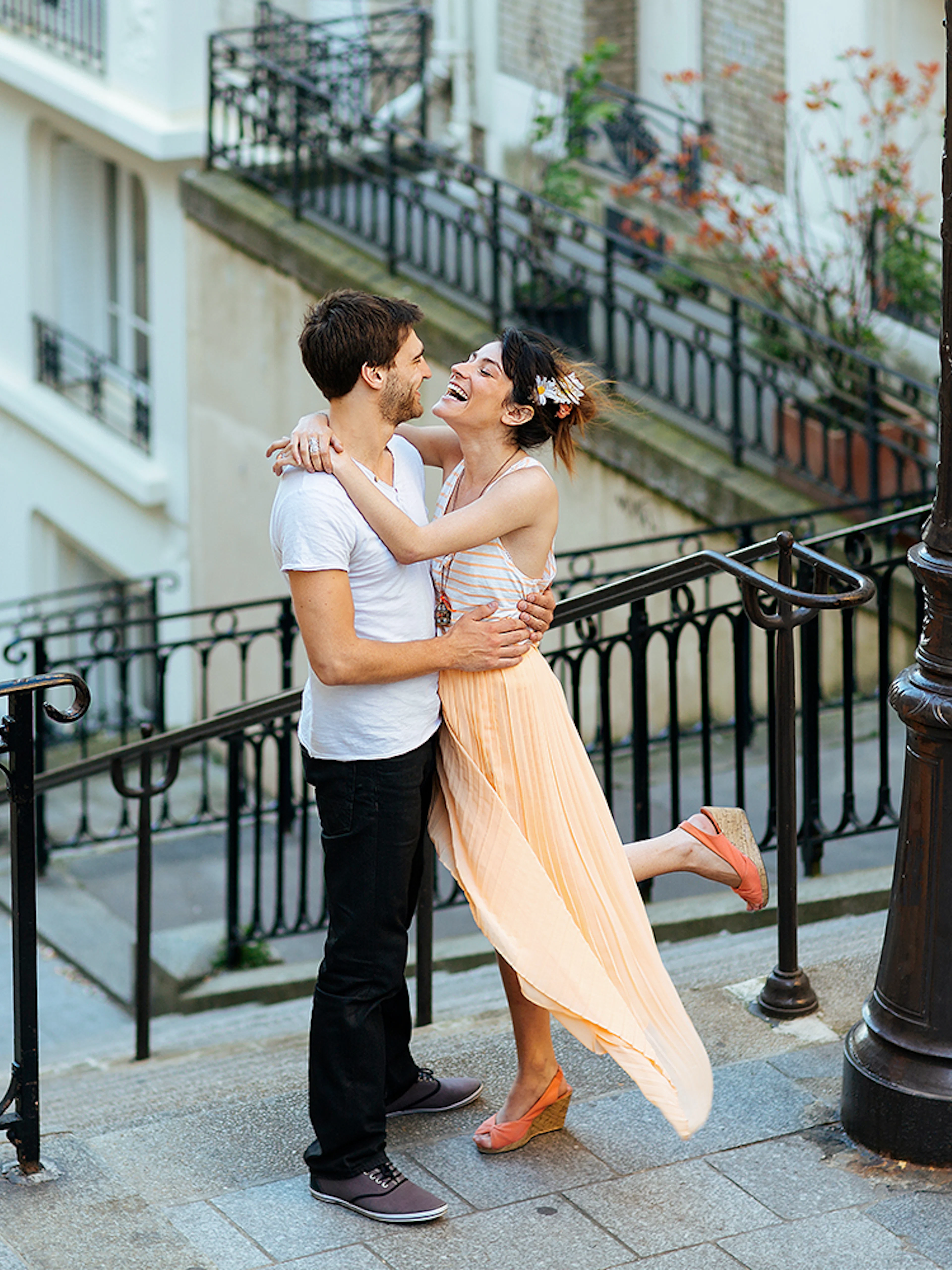 Couple embracing on Montmartre steps during professional photoshoot in Paris.