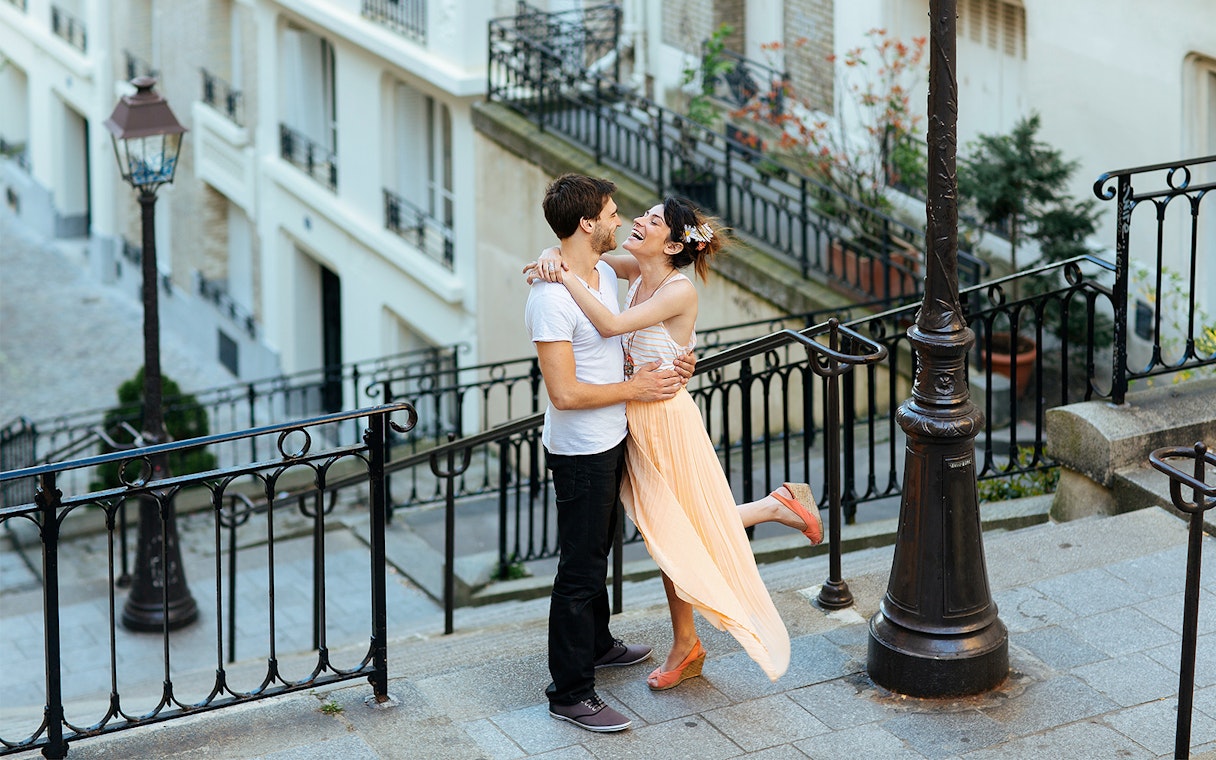 Couple embracing on Montmartre steps during professional photoshoot in Paris.