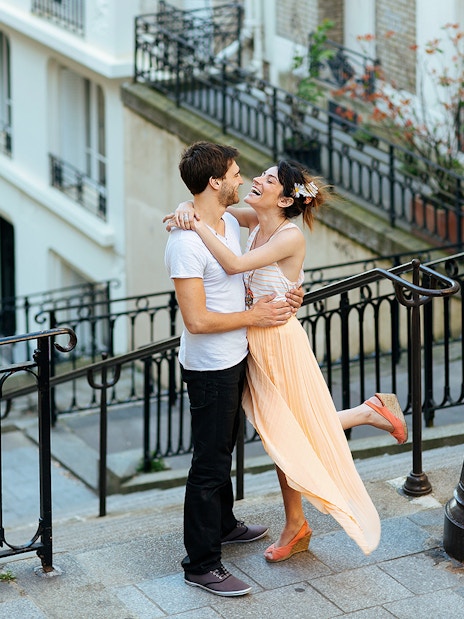 Couple embracing on Montmartre steps during professional photoshoot in Paris.