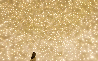Person gazing at illuminated installation at TeamLab Phenomena Abu Dhabi.
