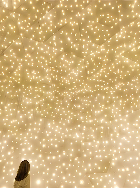 Person gazing at illuminated installation at TeamLab Phenomena Abu Dhabi.