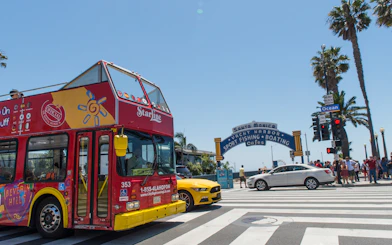 Red double-decker tour bus near Santa Monica Pier entrance, Los Angeles.