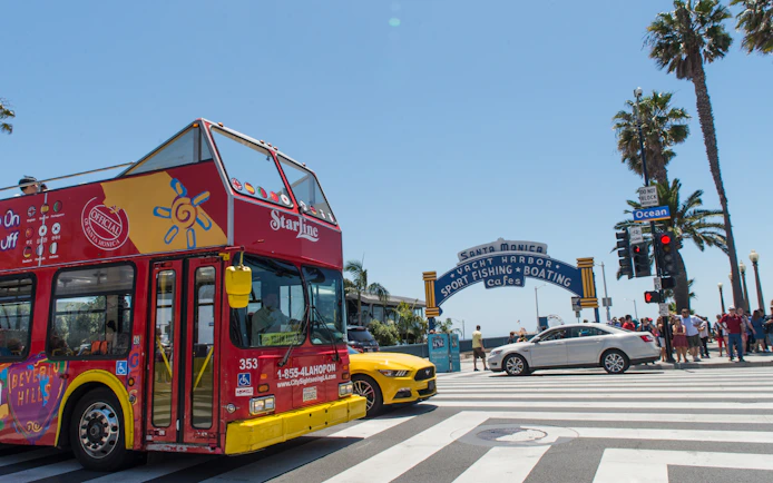 Red double-decker tour bus near Santa Monica Pier entrance, Los Angeles.