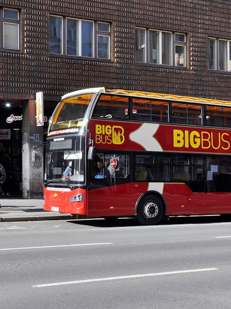 People waiting at a bus stop for the Big Bus Hop on Hop Off tour in Prague.