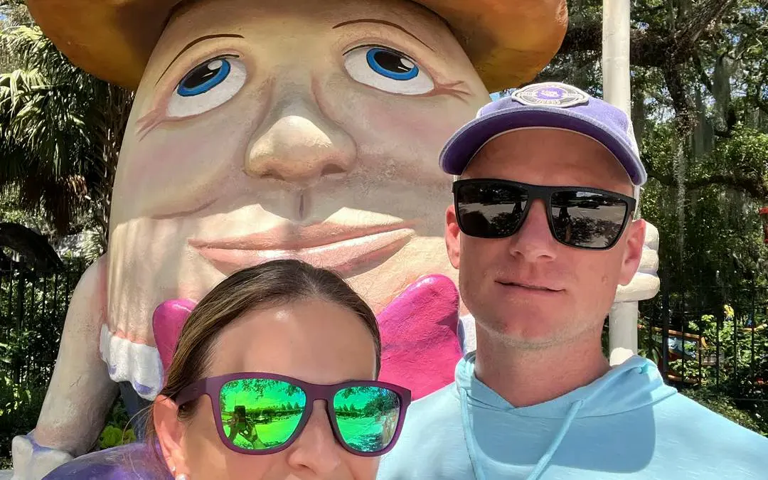 Humpty Dumpty statue with visitors in New Orleans park, part of city exploration game.