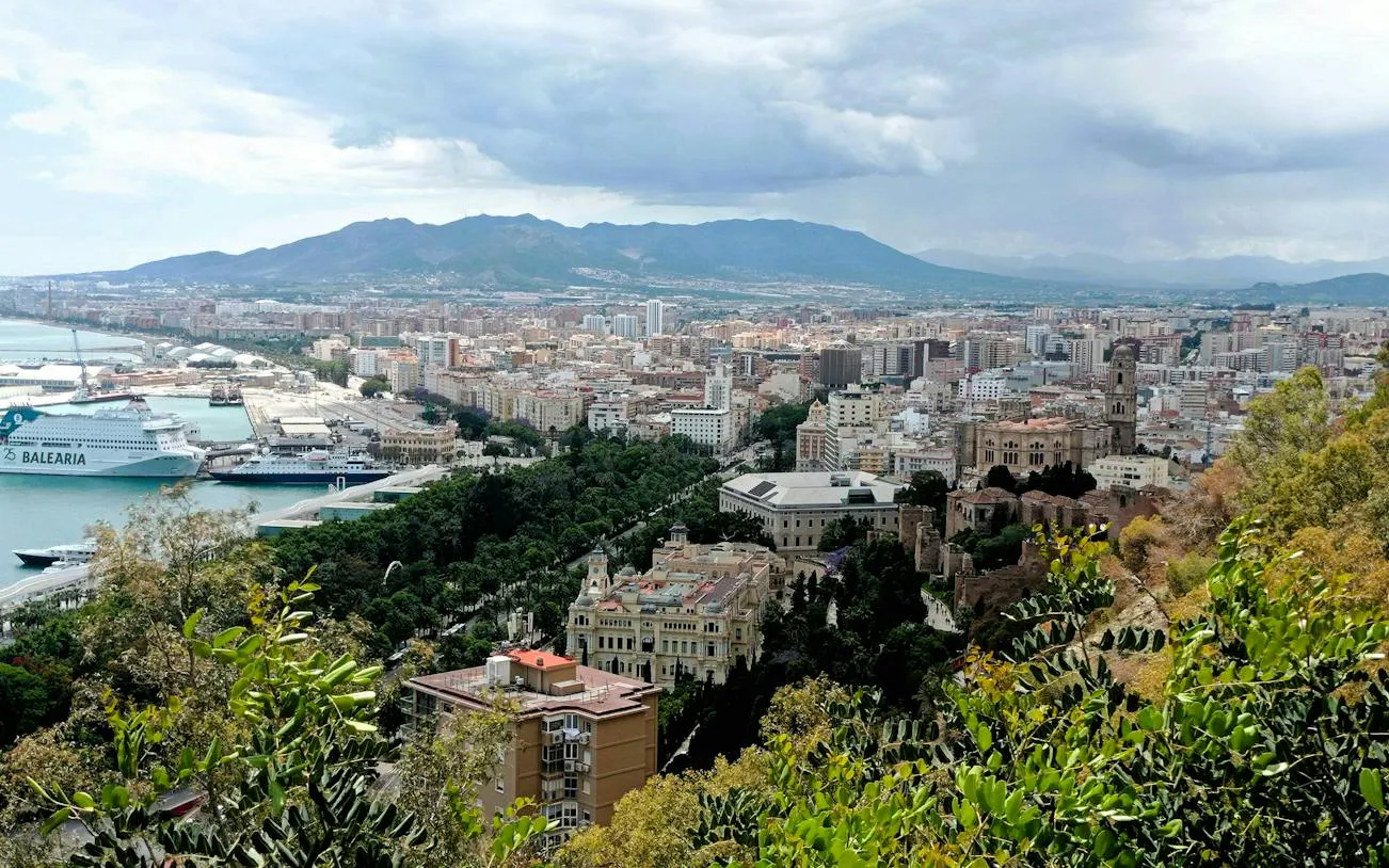 Aerial view of Malaga cityscape with port and historic buildings, part of the Malaga Picasso Heist game.