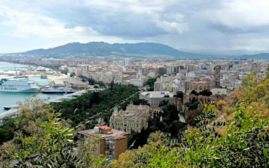 Aerial view of Malaga cityscape with port and historic buildings, part of the Malaga Picasso Heist game.