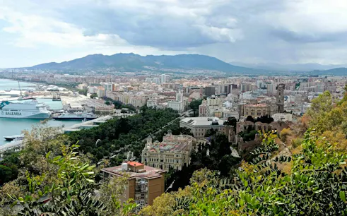 Aerial view of Malaga cityscape with port and historic buildings, part of the Malaga Picasso Heist game.