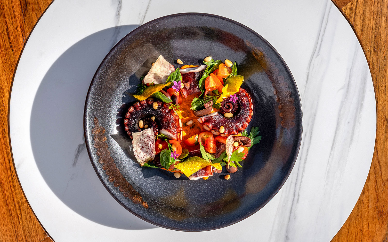 Grilled octopus with cherry tomatoes and herbs at Yona Beach Club, Phuket.