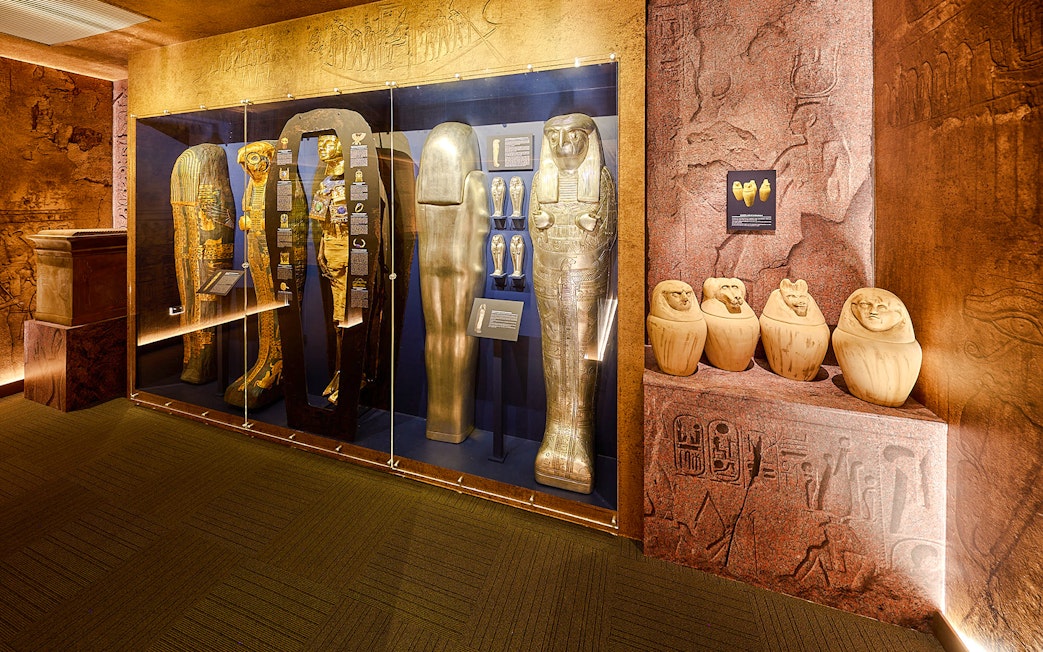 Golden sarcophagi and canopic jars in glass case at Tomb of the Pharaoh exhibit.