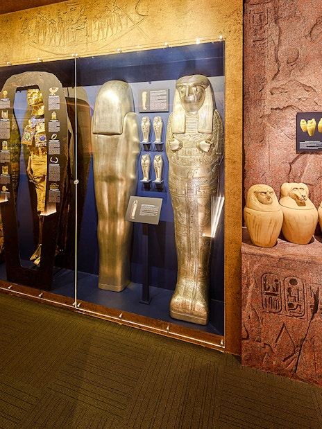 Golden sarcophagi and canopic jars in glass case at Tomb of the Pharaoh exhibit.
