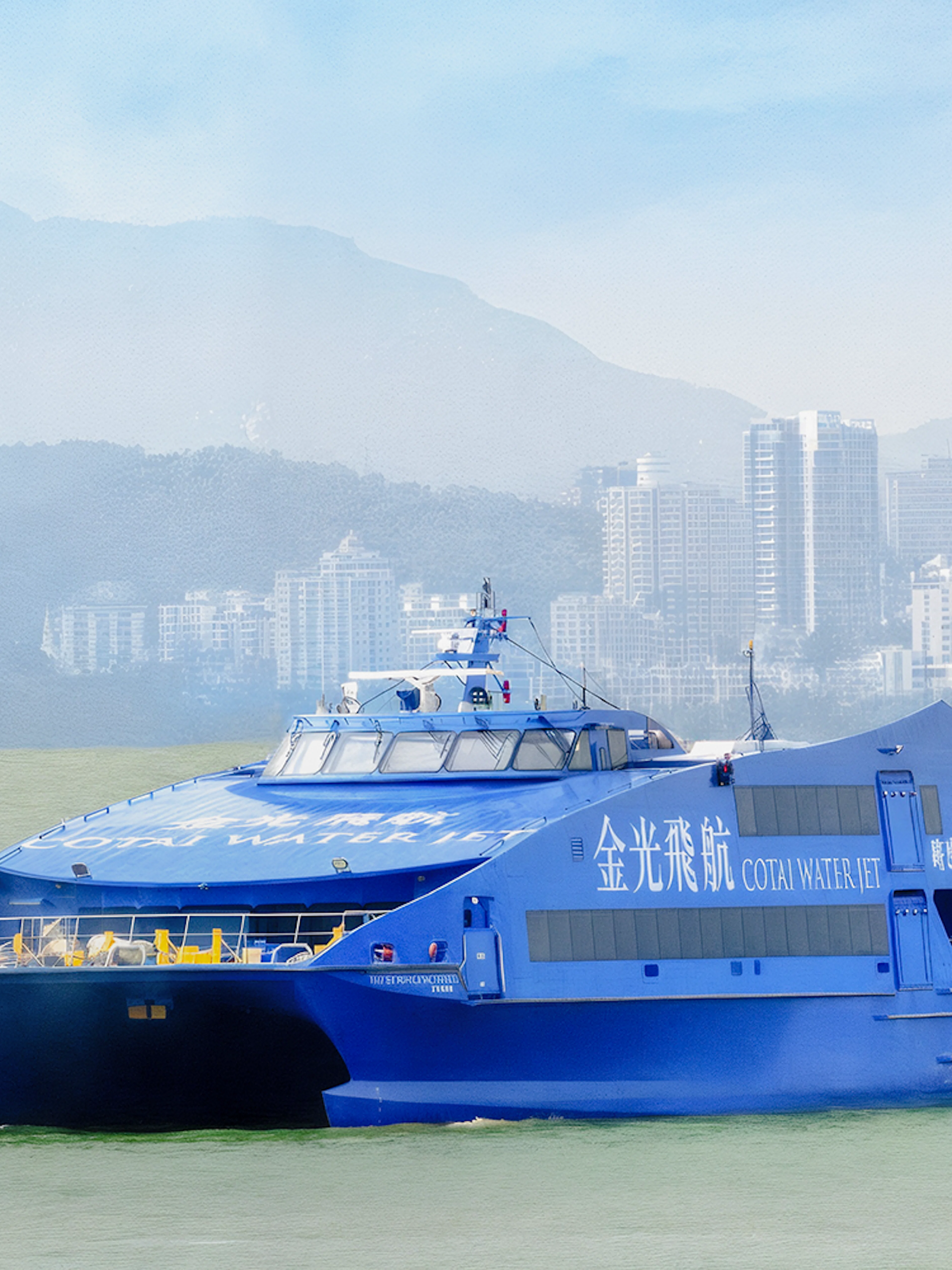 Cotai Water Jet ferry traveling between Hong Kong Island and Macau with city skyline in background.